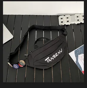 Detail of black nylon chest bag featuring white logo text and decorative badges on the strap