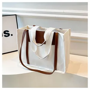 Detailed shot of white canvas tote bag with brown leather trim and FASHION BAG logo label