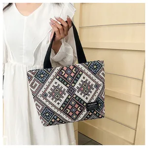 Detailed texture of multi-color woven geometric pattern on ethnic tote bag with logo tag