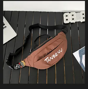 Brown nylon crossbody chest bag with round badges and white logo on a modern desk