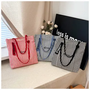 Detailed shot of striped canvas tote bags in red, blue and black with embroidery