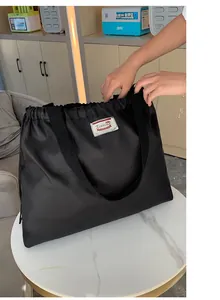 Detail der wasserdichten Nylon-Tragetasche mit Xiuxian-Aufnäher auf weißem Marmortisch