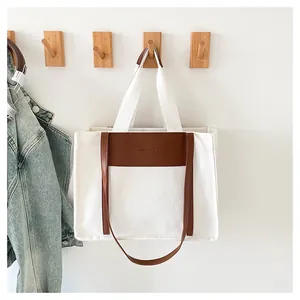 Detail of canvas tote bag featuring brown leather patch with FASHION BAG lettering