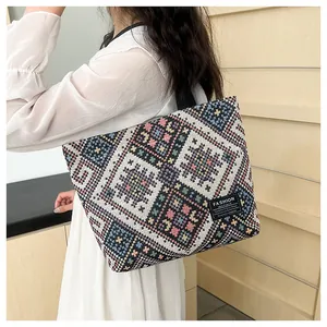 Detailed close-up of ethnic geometric weave pattern on canvas tote bag with black side tag