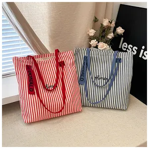 Detailed view of red and blue striped canvas tote bags with elegant embroidery