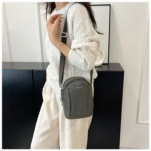 Close-up of lightweight nylon crossbody bag with adjustable strap and brand logo