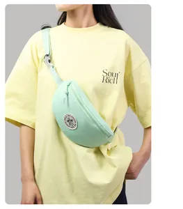Detail of light green canvas crescent waist bag with adjustable strap and star patch