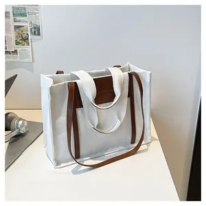 Detail of white canvas tote bag with brown leather handles and Fashion Bag embossed logo