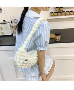 Détail d'un sac à bandoulière plissé beige orné d'un joli badge nuage arc-en-ciel