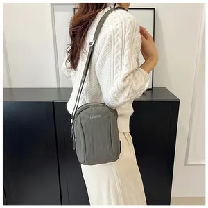 Olive green nylon crossbody bag styled with a white knit sweater on a female model
