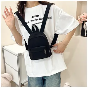 Dettaglio dello zainetto nero in nylon con tasca frontale a zip ed etichetta in tessuto
