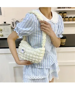 Détail d'un sac à bandoulière blanc matelassé avec badge arc-en-ciel et sangle plissée