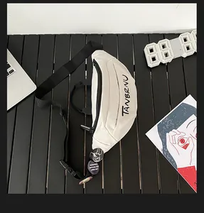 Flat lay of cream canvas chest bag with black typography and decorative round badges