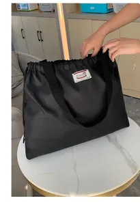 Detailansicht der schwarzen Nylon-Einkaufstasche mit Kordelzug und robustem Tragegriff