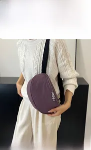 Detail of a purple nylon crescent bag with adjustable black strap worn as a crossbody bag