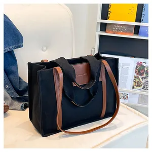 Detail of black canvas tote bag with brown leather accents and FASHION BAG emblem