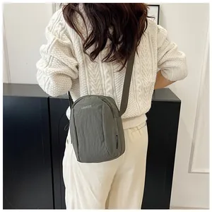 Olive green nylon crossbody bag showing the adjustable strap and back view on model
