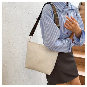 Close-up of beige faux leather tote bag with vintage patterned jacquard wide shoulder strap