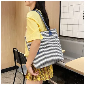 Detail of blue and white striped canvas tote bag with Humin text and sturdy dark straps