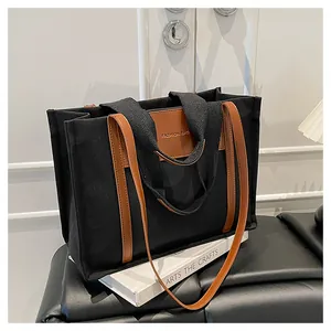 Detail of canvas tote bag showing brown leather patch and dual strap texture design