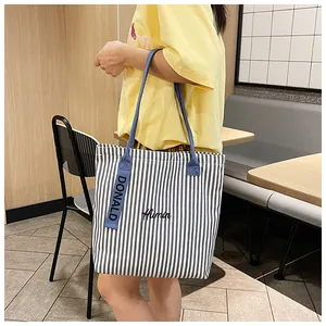 Detail of striped canvas tote bag with blue handles and Humin embroidery detail