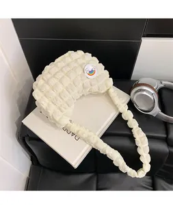 Détail du sac nuage blanc cassé avec texture bulles et badge arc-en-ciel sur un livre