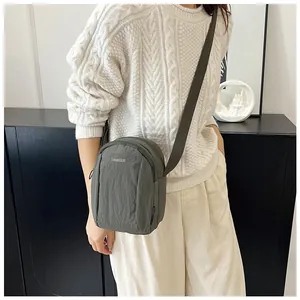 Detail of grey nylon crossbody bag shown on model with adjustable strap and logo