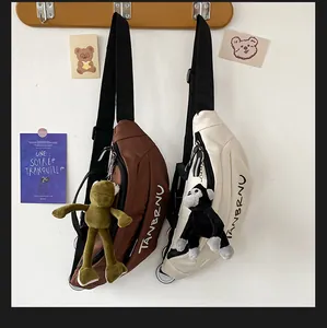 Detail view of nylon crossbody bags in brown and beige with cute plush doll keychains