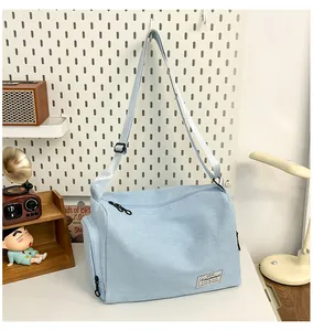 Close-up of a light blue canvas shoulder bag with adjustable strap and side zipper detail