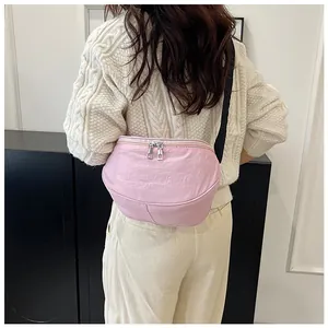 Pink nylon crescent crossbody bag with silver double zippers shown on shoulder