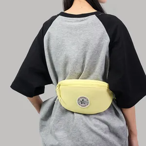 Pale yellow canvas fanny pack with a star patch logo worn by a model in casual wear