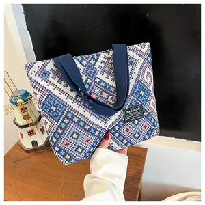 Detail of woven tote bag featuring colorful geometric patterns and durable blue handles