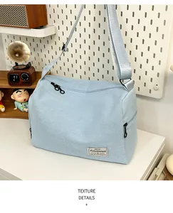 Detail of light blue canvas bag featuring adjustable wide strap and black metal zipper