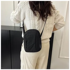 Detail of black nylon crossbody bag featuring textured fabric and adjustable strap
