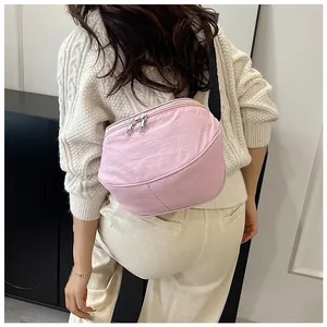 Detailed back view of a light pink crescent crossbody bag worn by a model in a studio