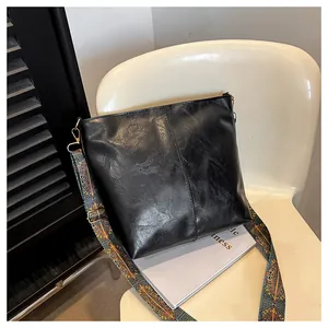 Detail of black PU leather tote with vintage texture and colorful ethnic wide shoulder strap