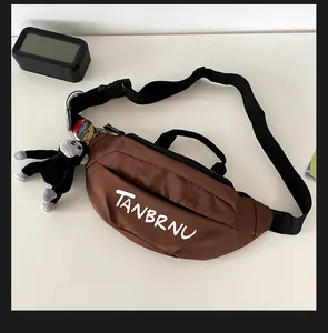 Detailed view of brown crossbody bag with adjustable strap and small monkey plush charm