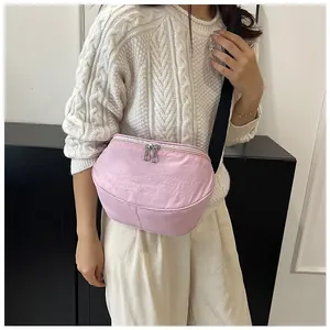 Detail of pink nylon crescent bag featuring dual zippers and adjustable black strap