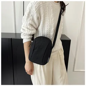 Close-up of black waterproof nylon crossbody bag with adjustable strap on white sweater