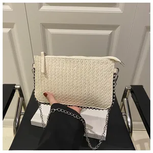 Gros plan du sac tissé crème avec bordure perlée argentée et bandoulière chaîne