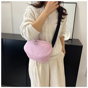 Close-up of pink crossbody bag showing metal double zippers and adjustable strap