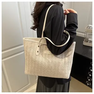 Close-up of the beige woven tote bag with white faux leather straps and metal rivets