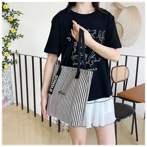 Detail of black and white striped canvas tote with Donald tag and ribbon handle
