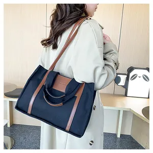Detail of minimalist canvas tote bag in black and brown styled with a trench coat