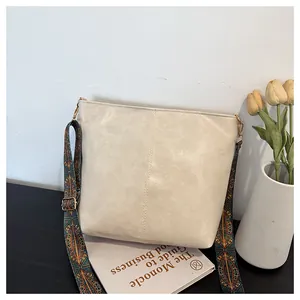 Detail of cream leather tote bag featuring a wide colorful geometric patterned shoulder strap