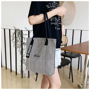Detail of black and white striped canvas tote bag with Donald embroidery and ribbon strap