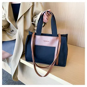 Close-up of canvas tote bag with brown leather panel detail and Fashion Bag text