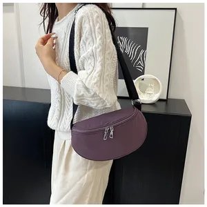 Close-up of purple nylon crescent bag with silver double zippers and adjustable strap