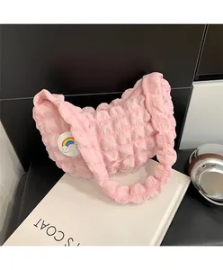 Détail du sac nuage plissé rose avec écusson arc-en-ciel et surface en tissu texturé