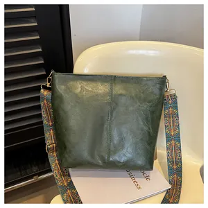 Detail of dark green vintage tote bag with colorful ethnic style wide shoulder strap